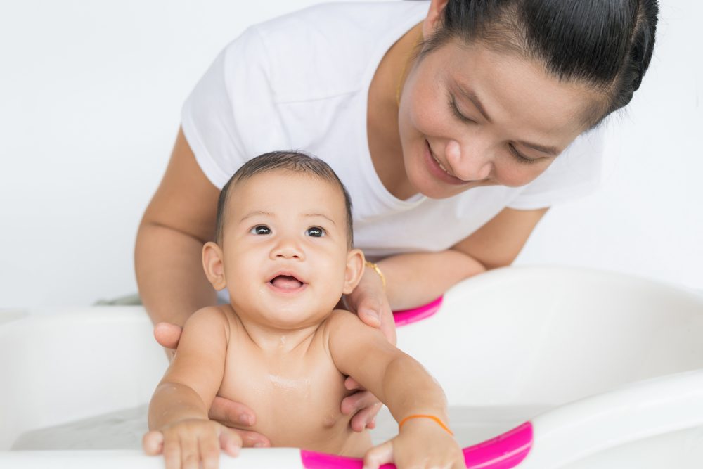 Happy baby taking a bath playing with mother washing little boy. Young child in a bathtub.